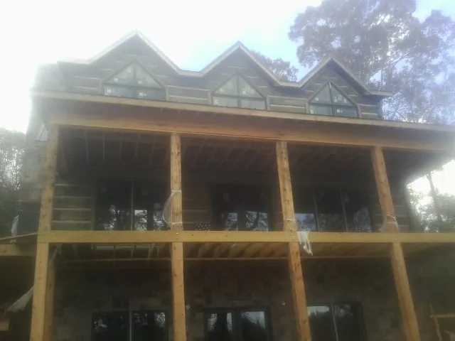 Dormers and porch framing on a large log home under construction — Roof Coating work by our crew in Groveland